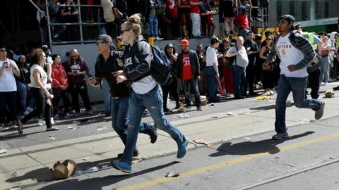 Police and spectators run as crowds scattered after reports of shots fired in the area where thousands gathered in Nathan Phillips Square