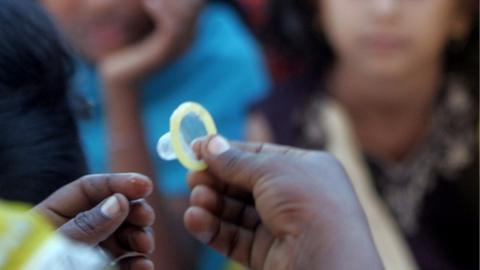 A volunteer at Nagarsoga village demonstrates use of a condom during a training programme on safe sex practices and HIV/AIDS in Latur in Maharashtra in 2008