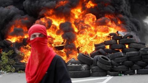 A protester stands in front of blazing tyres in Montegro