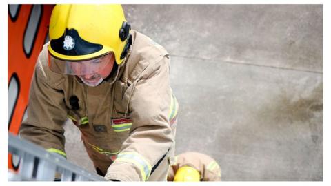 Firefighters climb a ladder