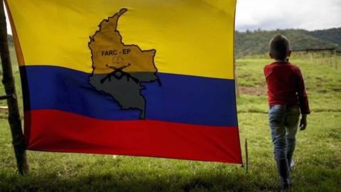 A little boy stands next to the FARC-EP flag in Marquetalia on 27 May, 2017.
