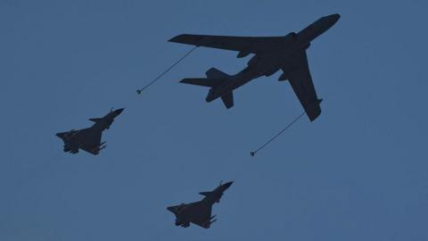 A Xian H-6U in-flight refueling tanker (C) flies in formation with a pair of Chengdu J-10 multirole fighte