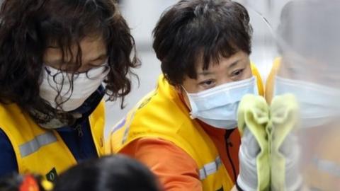 Workers disinfect a screen door to help prevent the spread of the COVID-19 coronavirus, at a subway station in Seoul on March 11, 2020.