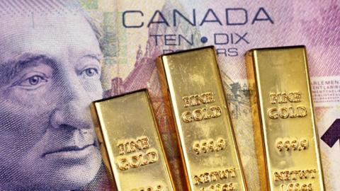 A close up image of a purple Canadian ten dollar bill with three small gold ingots