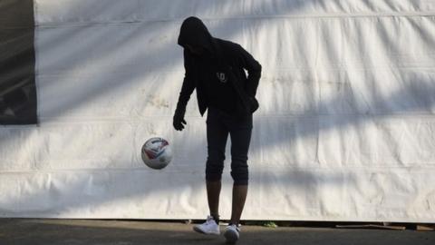 A Central American plays with a ball at a stadium-turned-shelter during a stop in the journey, in Mexico City on 7 November, 2018