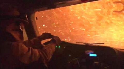 As burning ash pelts their vehicle, video shows firefighters in California drive through the flames.