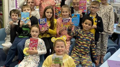 A group of children each holding a book