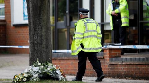 A police officer walks past floral tributes to British MP David Amess, who was stabbed to death during a meeting with constituents, outside the Belfairs Methodist Church, in Leigh-on-Sea, Britain,