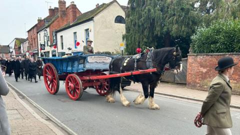 Eric Freeman's coffin being pulled through the streets on a waggon by a shire horse