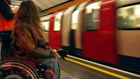 A wheelchair user waits for a tube train