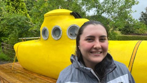 Volunteer Caroline McNamara in front of a yellow fibreglass submarine that was used in a search of Loch Ness in 1969