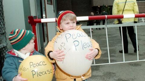 Children holding balloons with the word 'peace' on them