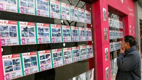 A man looks at a board with the various prices of a Chinese traditional courtyard dwelling, or Siheyuan, for sale and rent in Beijing, 18 December 2007