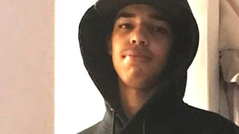 Taye Faik, a teenager wearing a back cap and hoodie