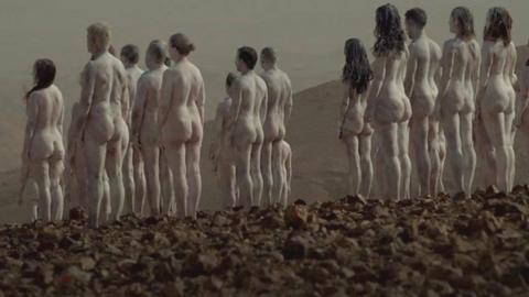 Naked people painted white and stood near the Dead Sea