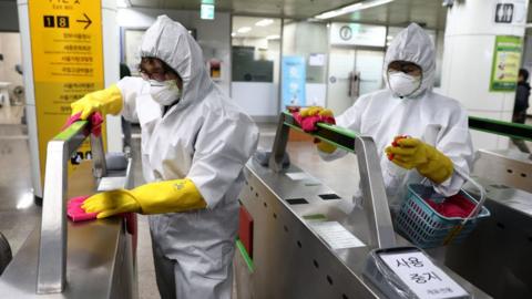 Disinfection professionals wearing protective gear spray anti-septic solution against the coronavirus (COVID-19) at a sybway station