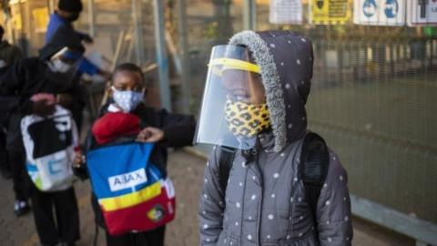 Children queue outside a school in South Africa