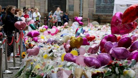 People pay their respects and lay flowers at a memorial for the victims of the Manchester bombing at St Ann"s Square