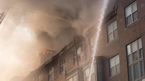 water hose sprays onto burning building