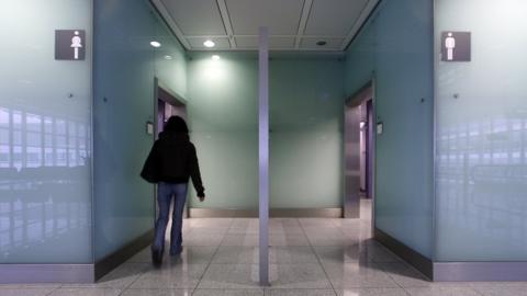 A woman walks into a public toilet