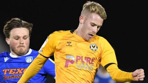 Ollie Cooper of Newport County is tackled by Noah Chilvers of Colchester United