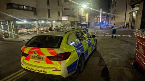 A yellow and blue police car in the foreground. 