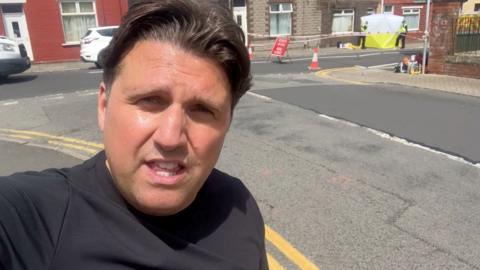 Jordan Davies with a forensic tent on a residential street in the background