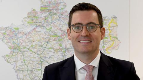 PCC Dan Price in front of a map of Cheshire