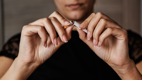 Person breaking cigarette in half