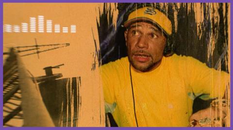 Musician Goldie wearing headphones and mixing records.