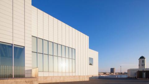 The image shows the outside of an art gallery against a deep blue sky.