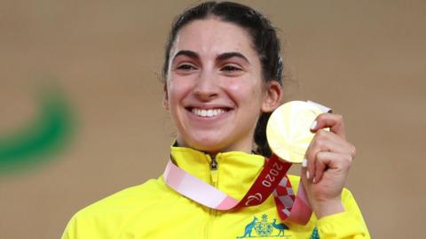 Paige Greco, in a bright yellow Team Australia jacket, poses with her gold medal at the Tokyo 2020 Paralympic Games in Izu, Japan