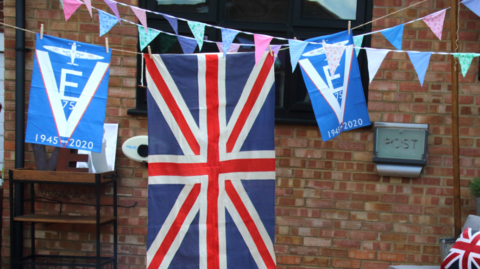 A union jack and commemorative flags shown outside a house to mark the 75th anniversary of VE Day in 2020