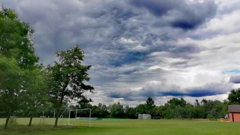 Football field with trees and cloudy skies