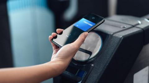 Woman taps mobile phone on TfL ticket barrier