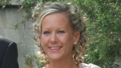 Gillian Morand stands outside in front of a tree. She has blonde curly hair.