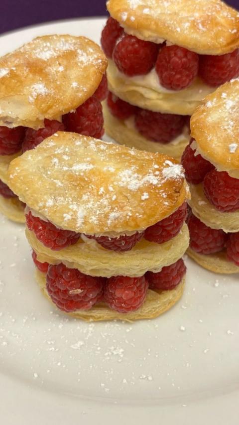 Close up of three-tired puff pastry circles with raspberries in the middle of each layer