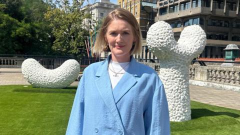 Alice Walters in a blue blazer standing front of a white sculptures.