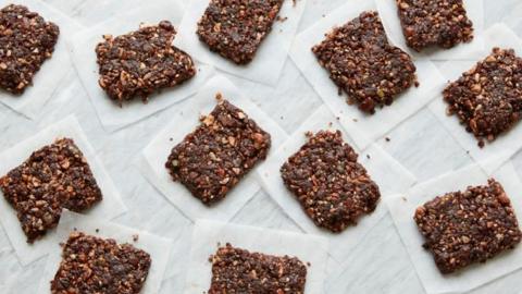 Chocolate and nut energy bars on squares of baking paper on a white background