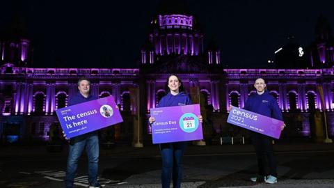 Dr David Marshall (left), Shauna Dunlop and Conor McKiernan posing in front of Belfast City Hall to promote the census