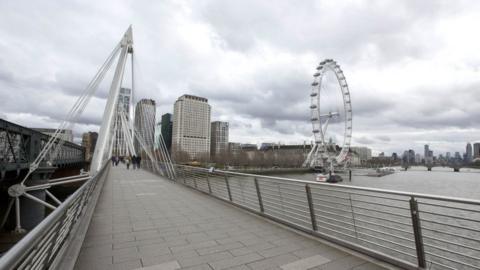 File image showing people walking in the distance on Jubilee Bridge, with the London Eye in the background