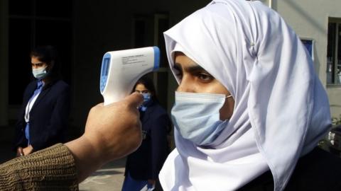 School staff check the temperatures of students as they arrive on the first day of school after the resumption of classes of higher grades in Islamabad, Pakistan, 18 January 2021