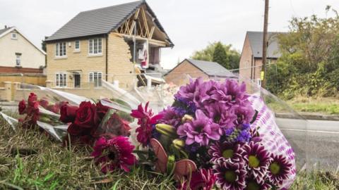 Flowers on the ground with damaged house in the background