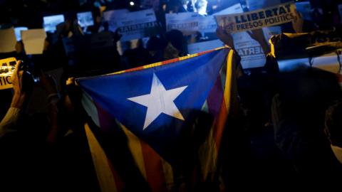 Protesters hold a Catalan pro-independence Estelada flag and signs reading "Freedom to political prisoners"