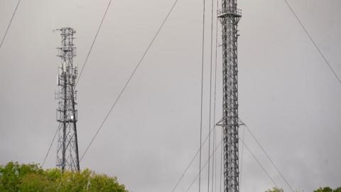 Tacolneston transmitter: Two grey metal tower structures - with a grey cloudy sky in the background.