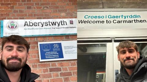 Jared Evitts in Carmarthen and Aberystwyth in front of two signs