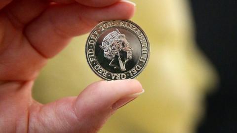 A man holding a pound coin