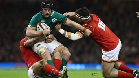 Two Welsh players tackling an Ireland player