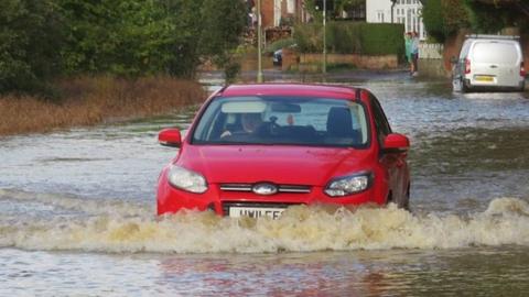 Red car driving through floodwater