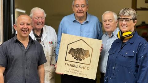 A group stand holding a Thame Shed sign